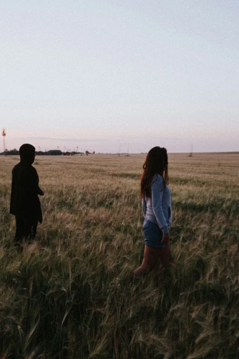 two people walking through an empty field at sunset
