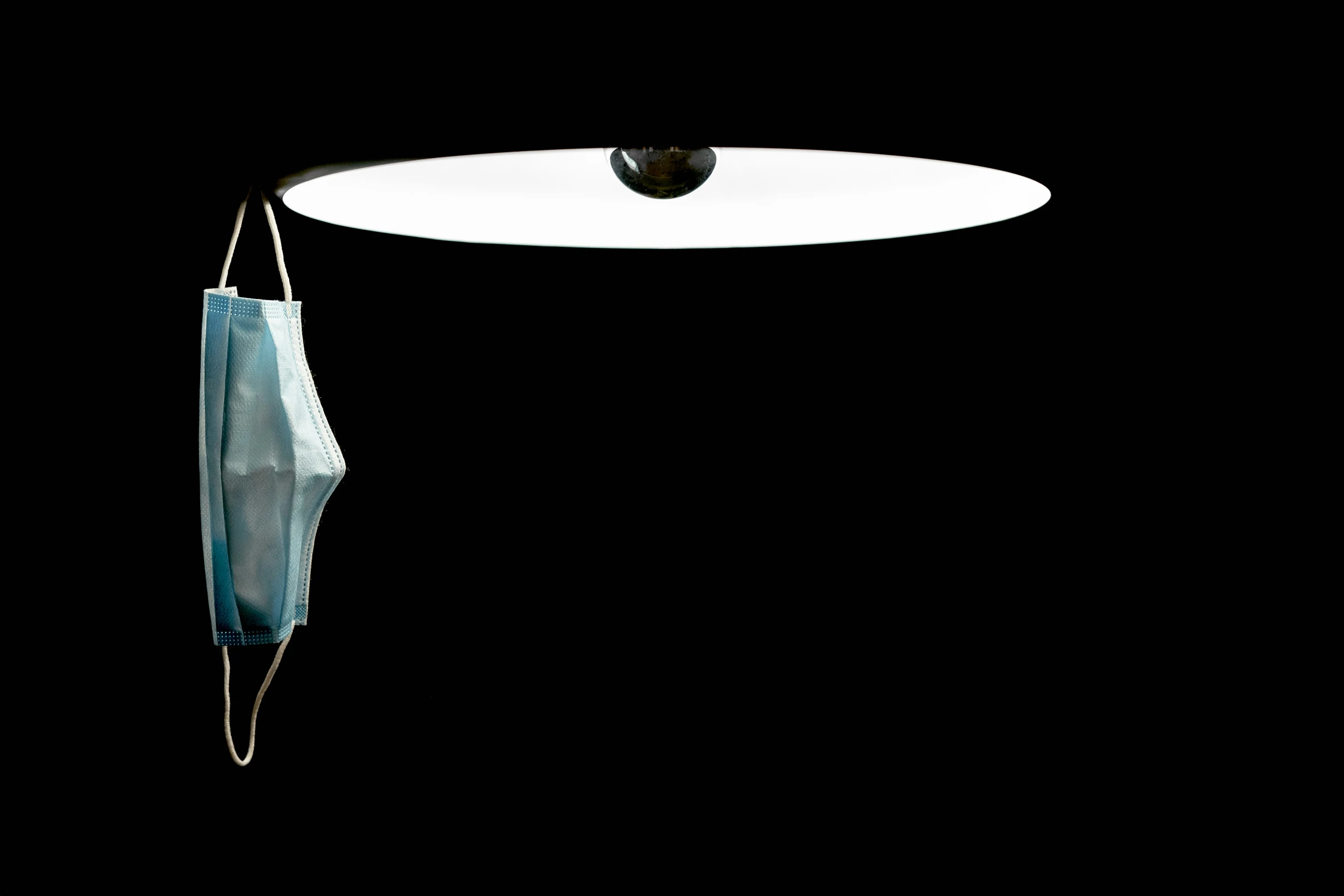 a suspended light on top of a black wall