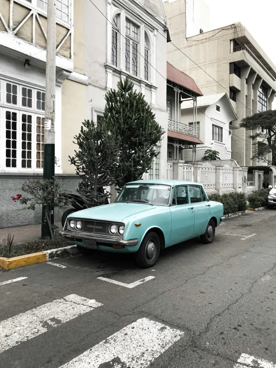 an old blue car is sitting by itself in the middle of the road