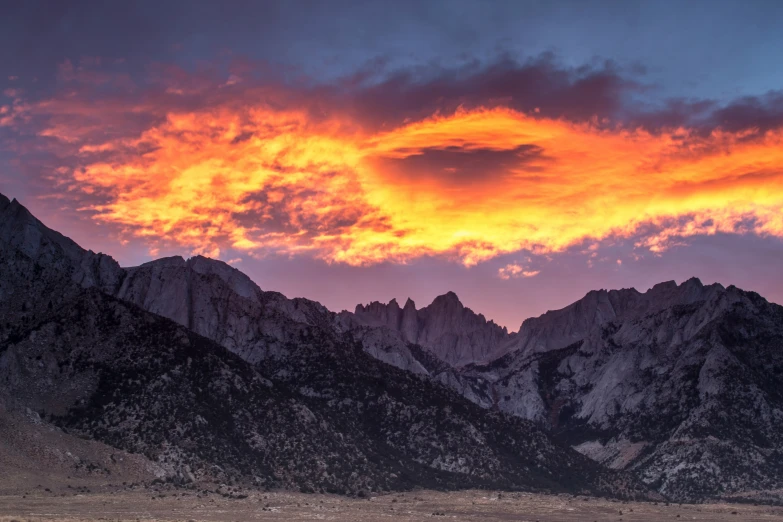 some mountains that are near one another with the sun setting behind them