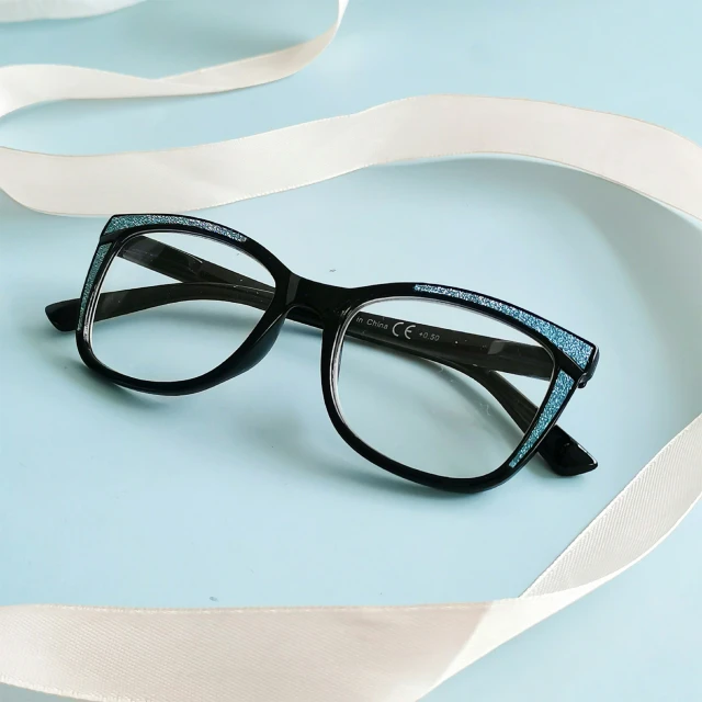 a pair of glasses sit on top of a piece of ribbon