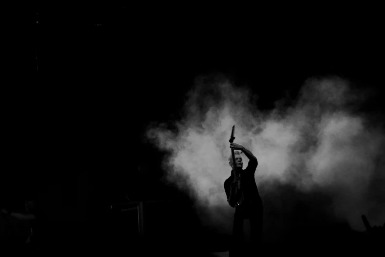 a man is holding a microphone standing in front of smoke