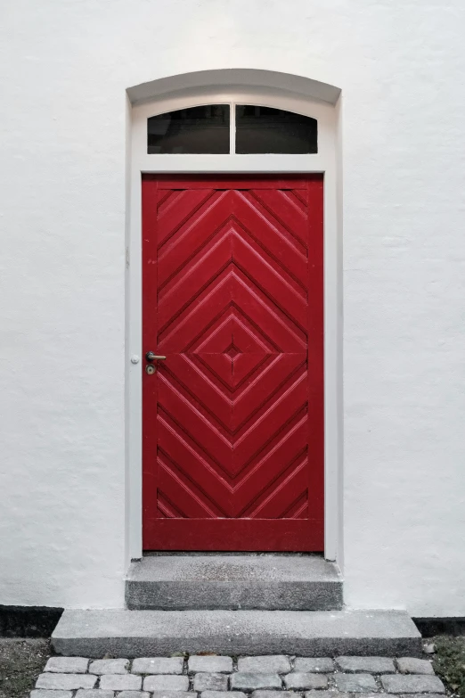 an empty brick walkway leading to a red door