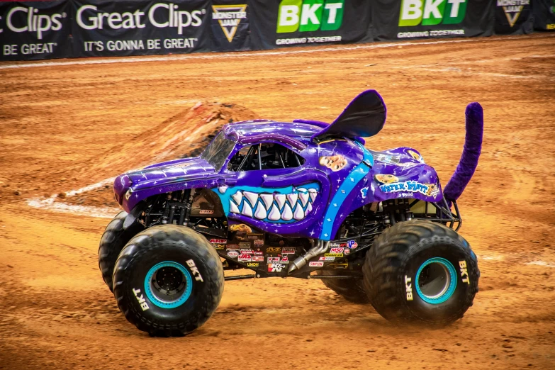 purple monster truck with big teeth moving on dirt