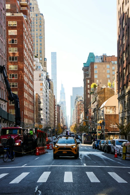 a taxi drives down an urban street with lots of tall buildings