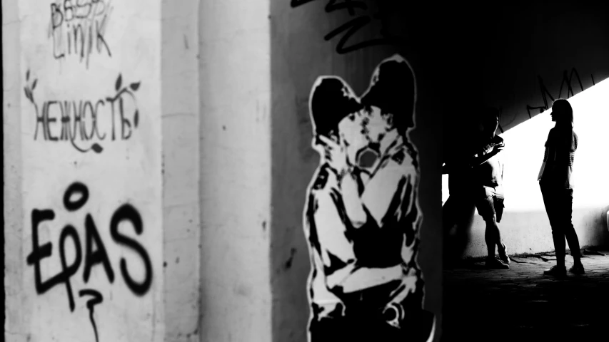 a woman standing under a bridge covered in graffiti