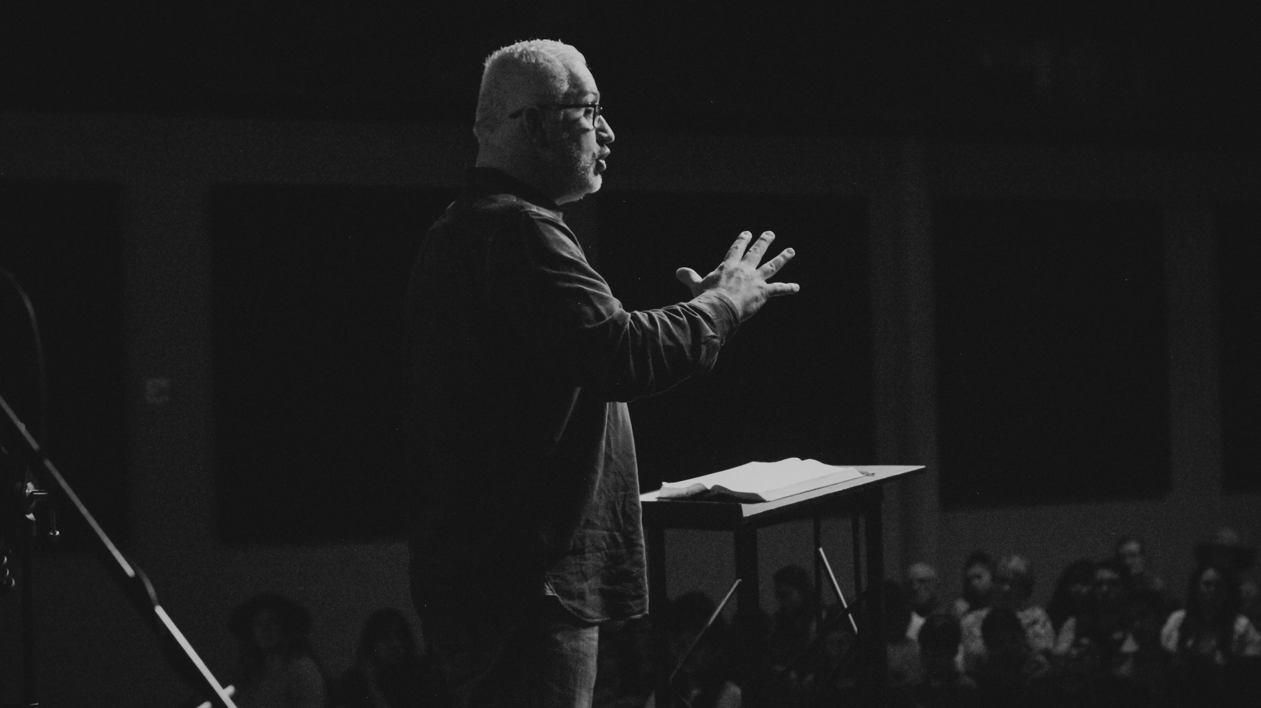 a man standing on top of a stage holding his hands out