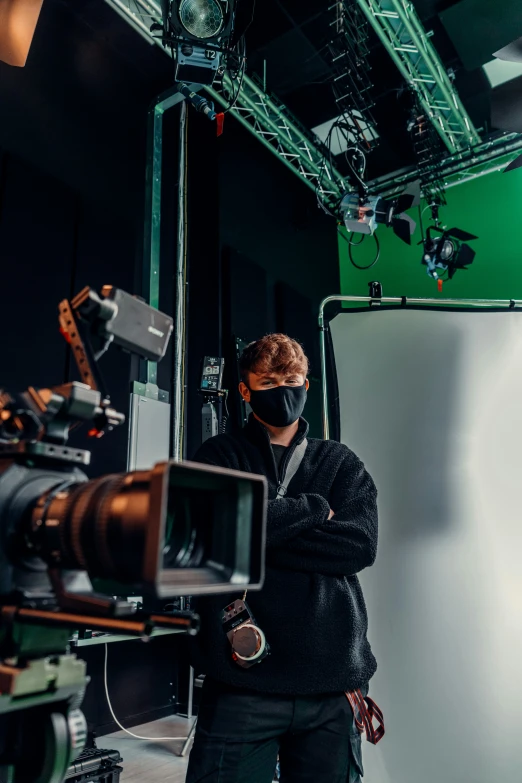 a man wearing a mask standing near a camera