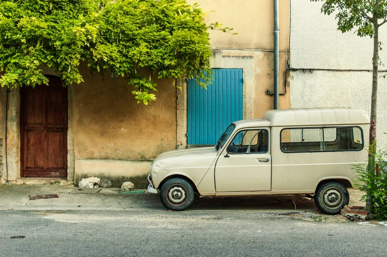 an old fashion mini van sits in front of an old building