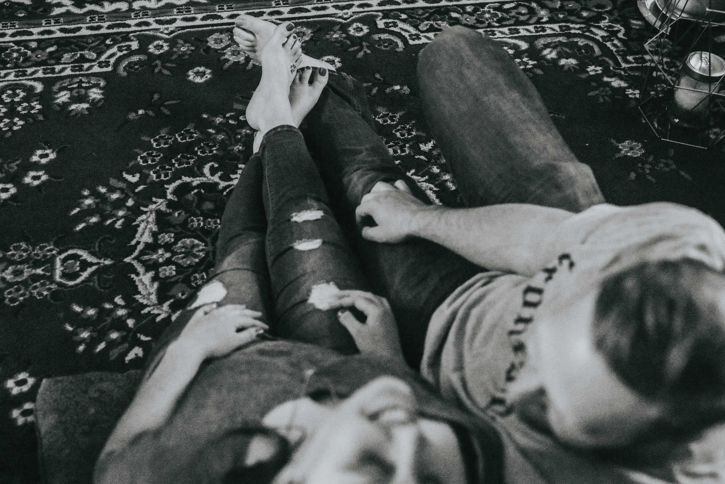 two people holding remotes while laying on a rug