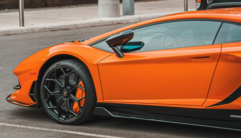 an orange sports car parked on the side of the road