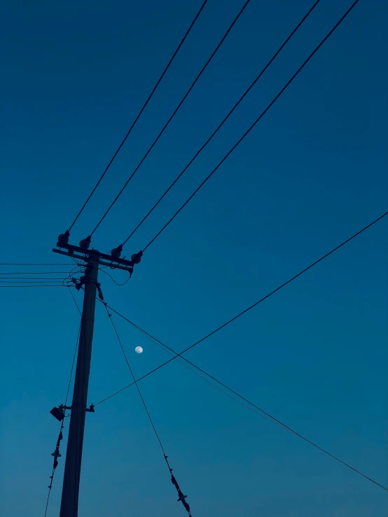 an electrical pole with a moon shining in the sky