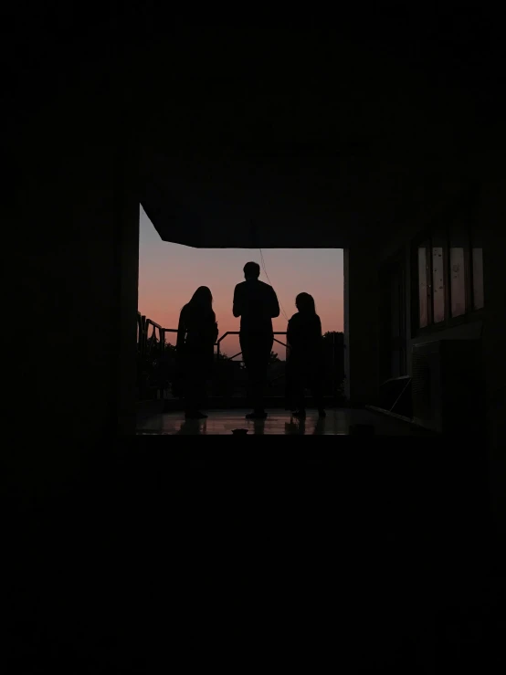 people standing together on top of a roof during a sunset