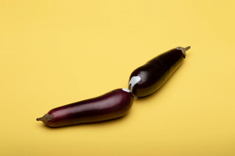 two eggplant halves on a yellow surface