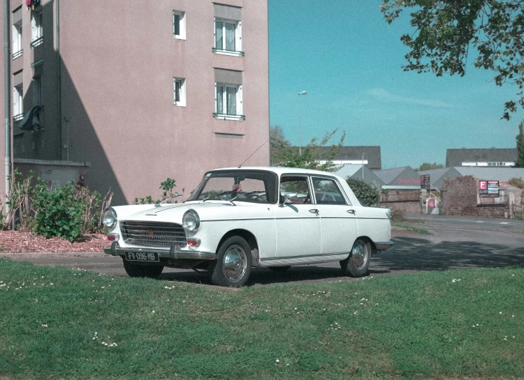 an old white car parked on the side of a street