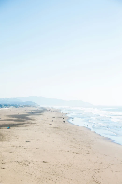 a man is walking along the beach on his surf board