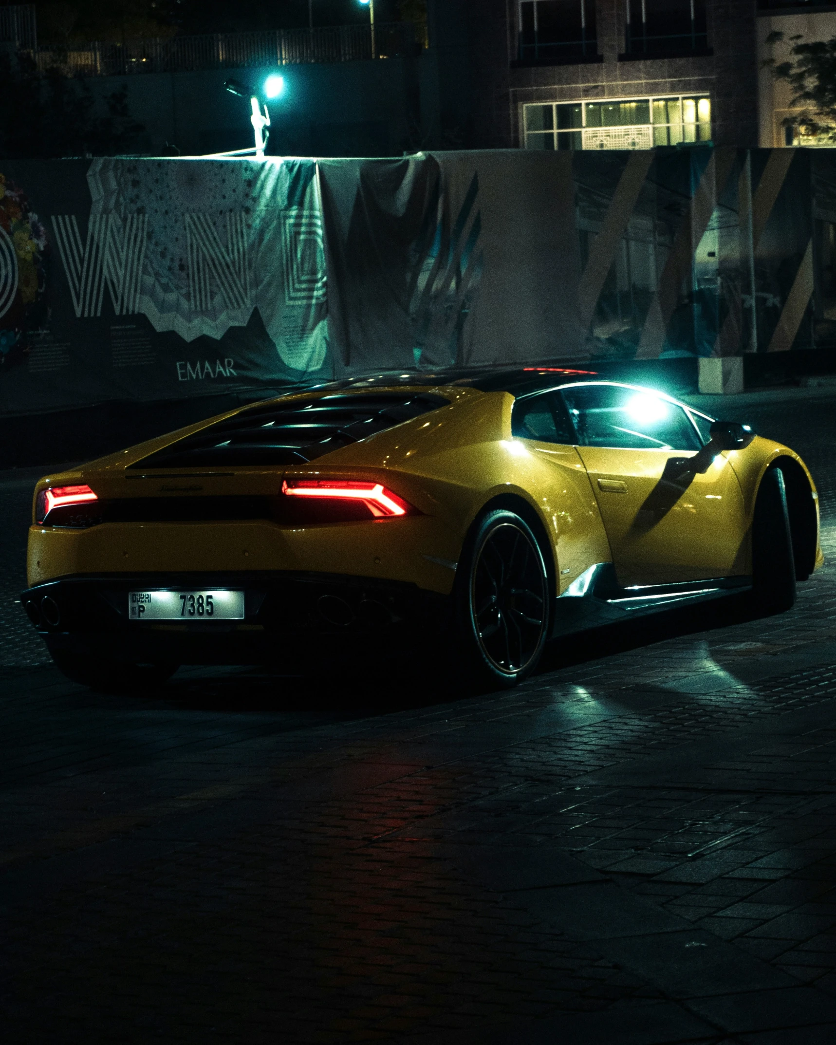 a yellow sports car with its lights on at night