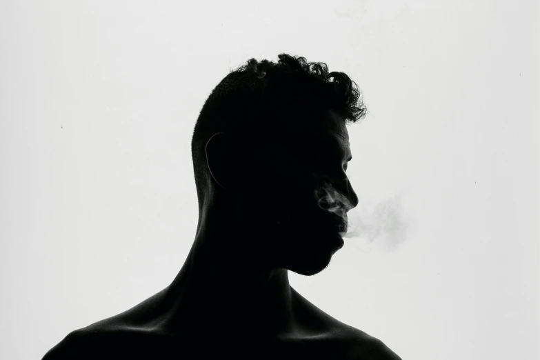 the silhouette of a man wearing a hat smoking a cigarette