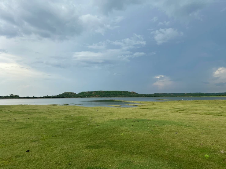 the lake is empty and very green with many people walking along the shore