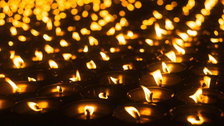 a close up of many lit candles, one lit in the center