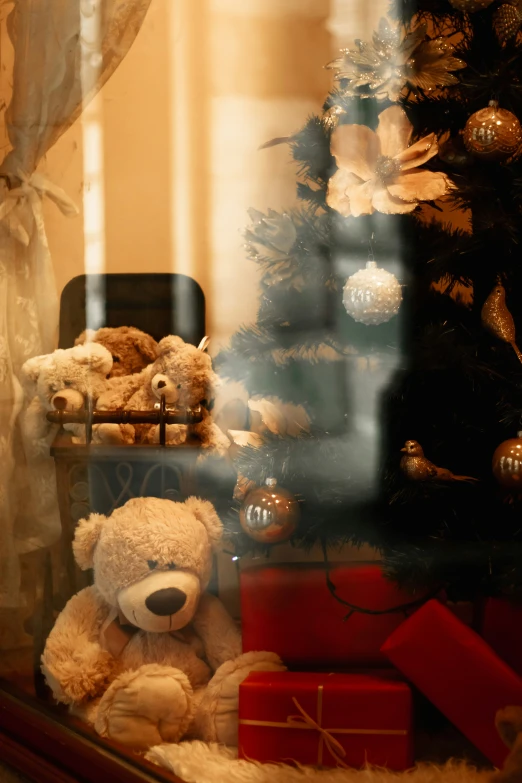 a teddy bear is sitting in front of the christmas tree