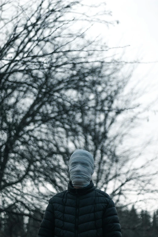 a person in winter clothes standing by a tree