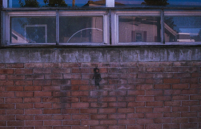 a red brick building with two windows reflected in it