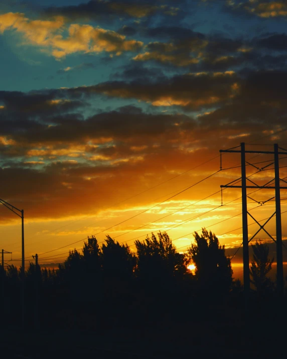 the sun is setting in the horizon behind electric lines