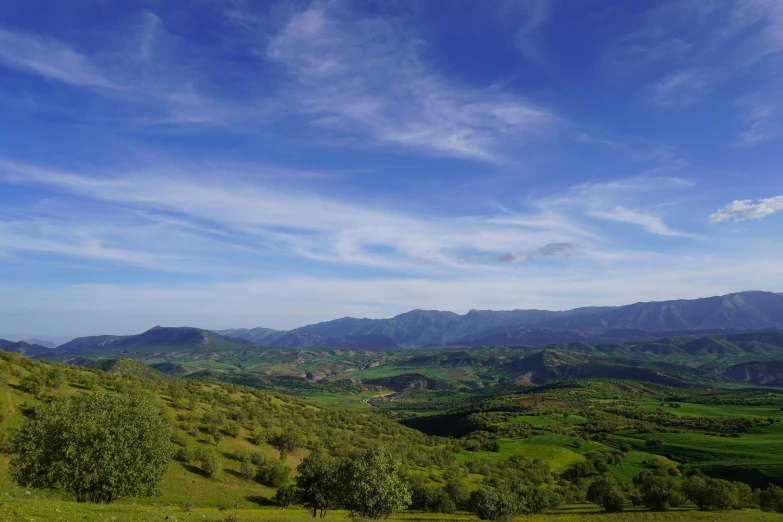 a lush green hillside with a large expanse of clouds