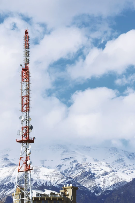 an outdoor radio tower with snow capped mountains in the background