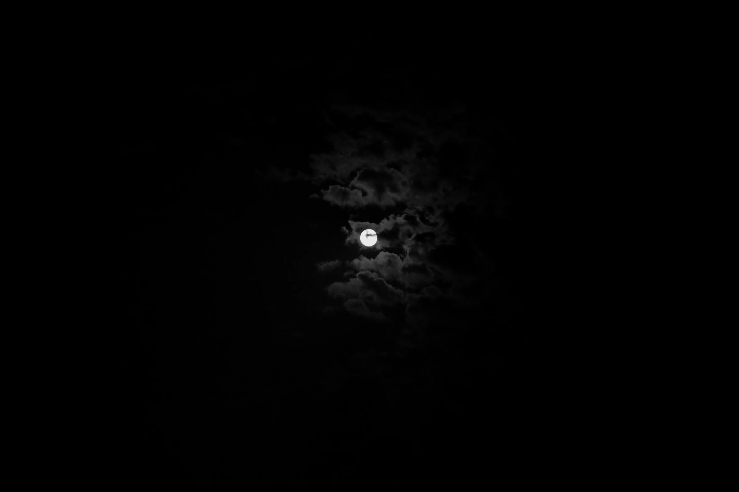 a moon in the dark clouds with a black background