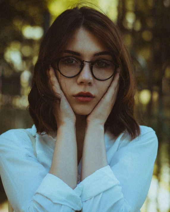 a woman with glasses leaning her head on her hands