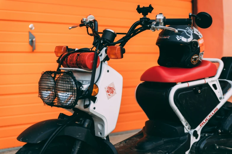 a white and black scooter and a red wall