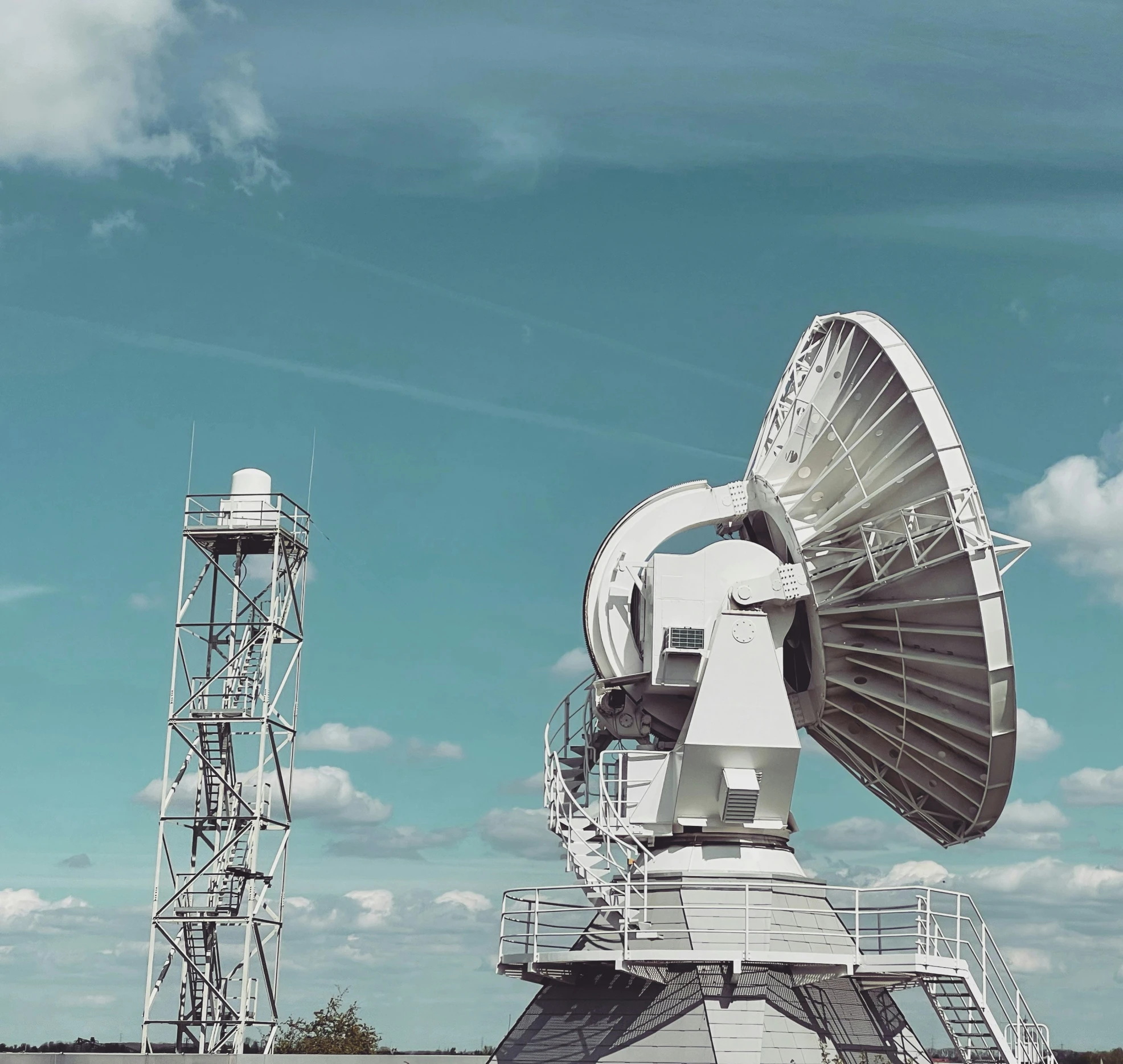 two white satellite dishes with a sky background