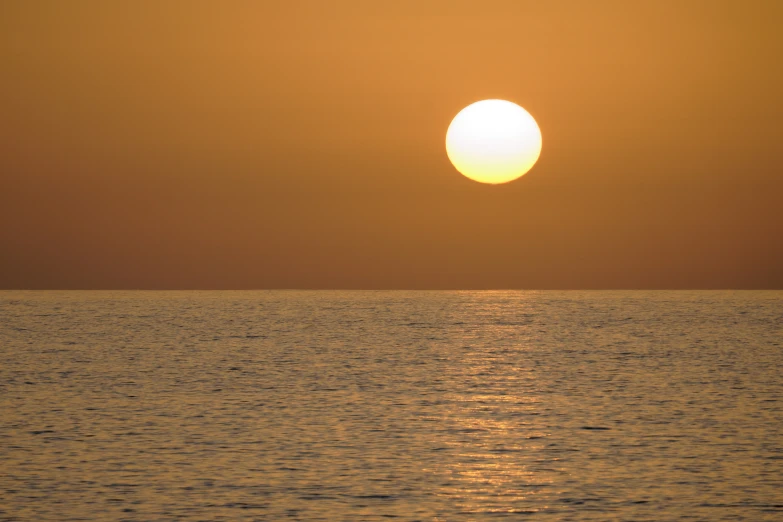 the sun set over the water during an orange sunset