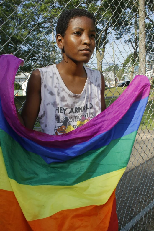 a boy wearing an african shirt holding a rainbow colored kite