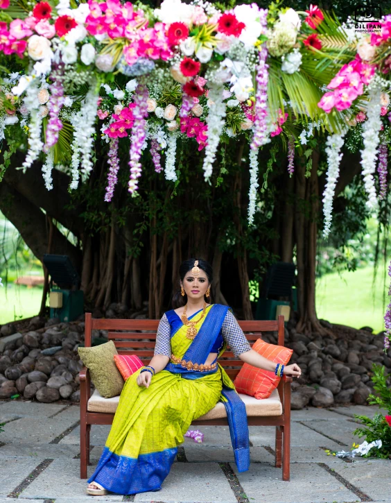 woman sitting on a bench in front of colorful flowers