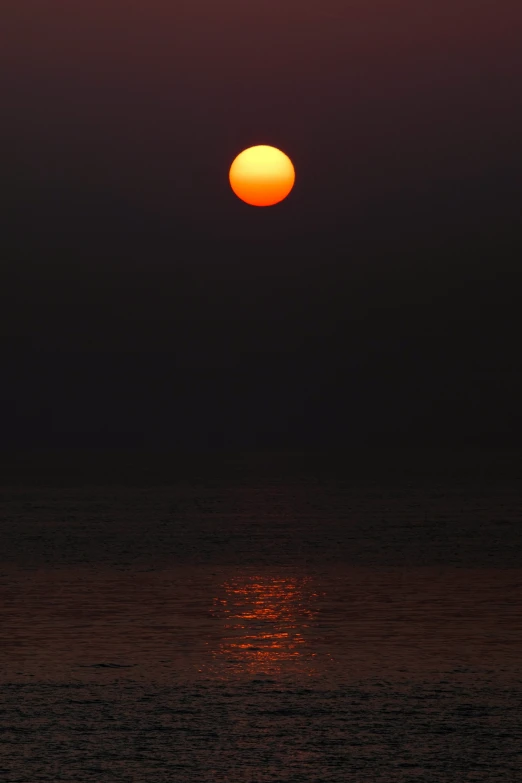 a bright orange sun setting on the ocean