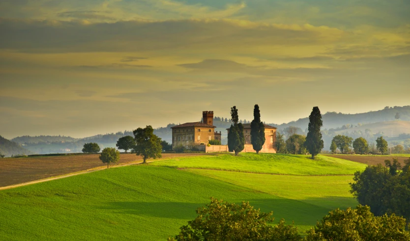 a lone building on a hill side with trees in the background