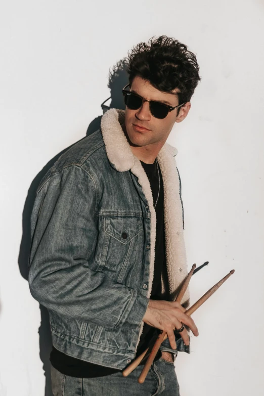 a man is holding three drumsticks and looking at the camera