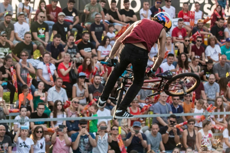 a man does tricks on his bike while an audience watches