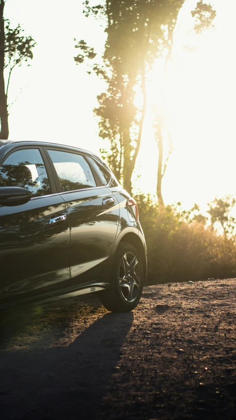 a black car parked on a street next to trees