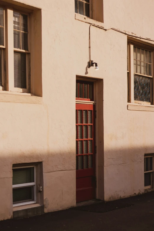 a red door is in the outside of this beige building