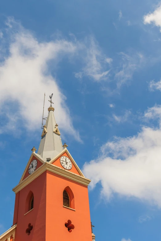 a steeple has a clock on it and is very orange