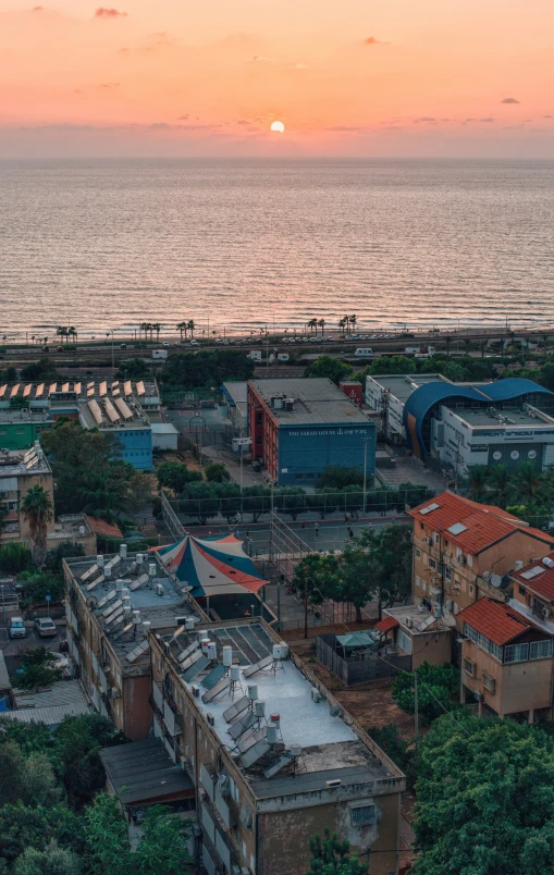 a sunset over some buildings on the coast