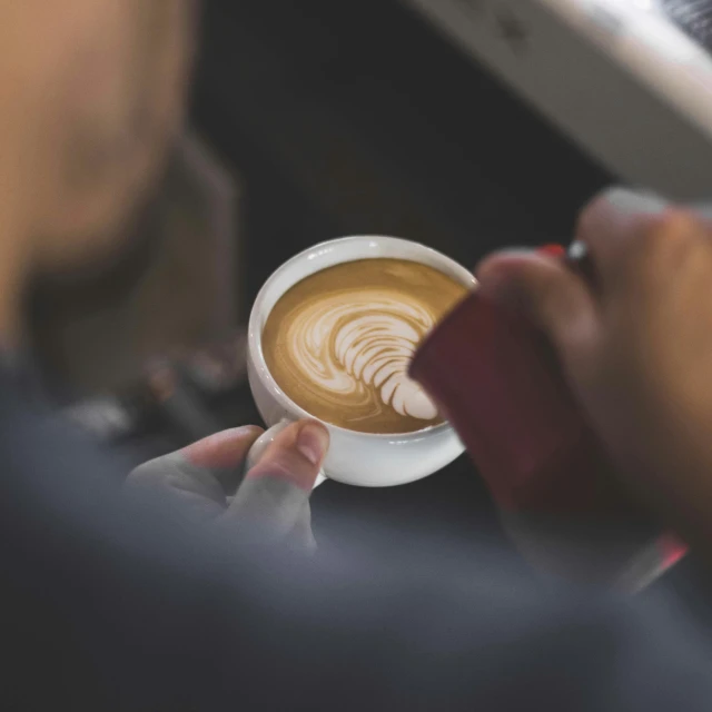 someone is holding out a white cup that has a pattern on it