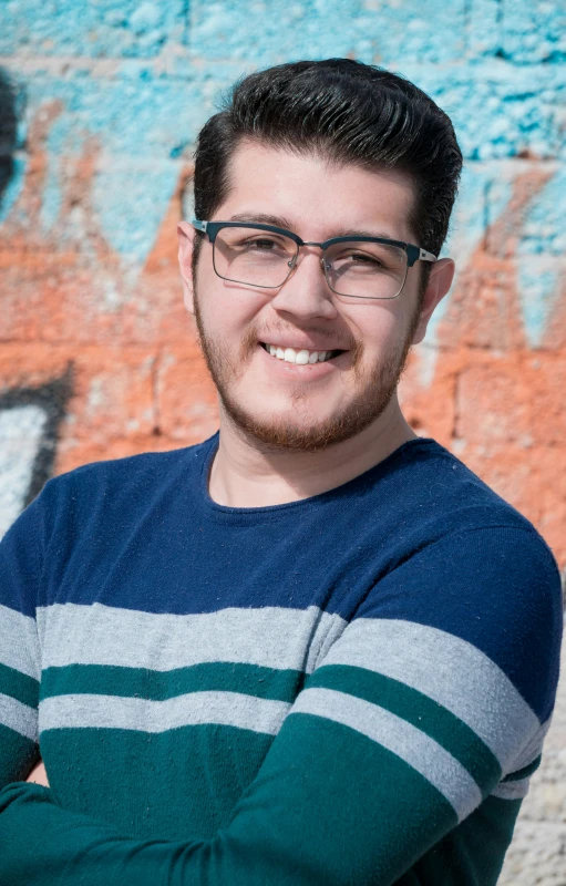 a man smiling for the camera in front of a graffiti wall