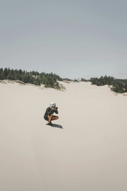 a person kneeling in the sand with a hat