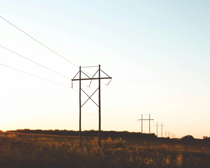 a row of power poles that are in the grass