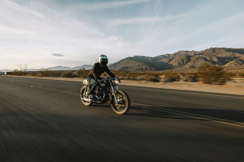 a motorcycle is riding on the road in front of mountains